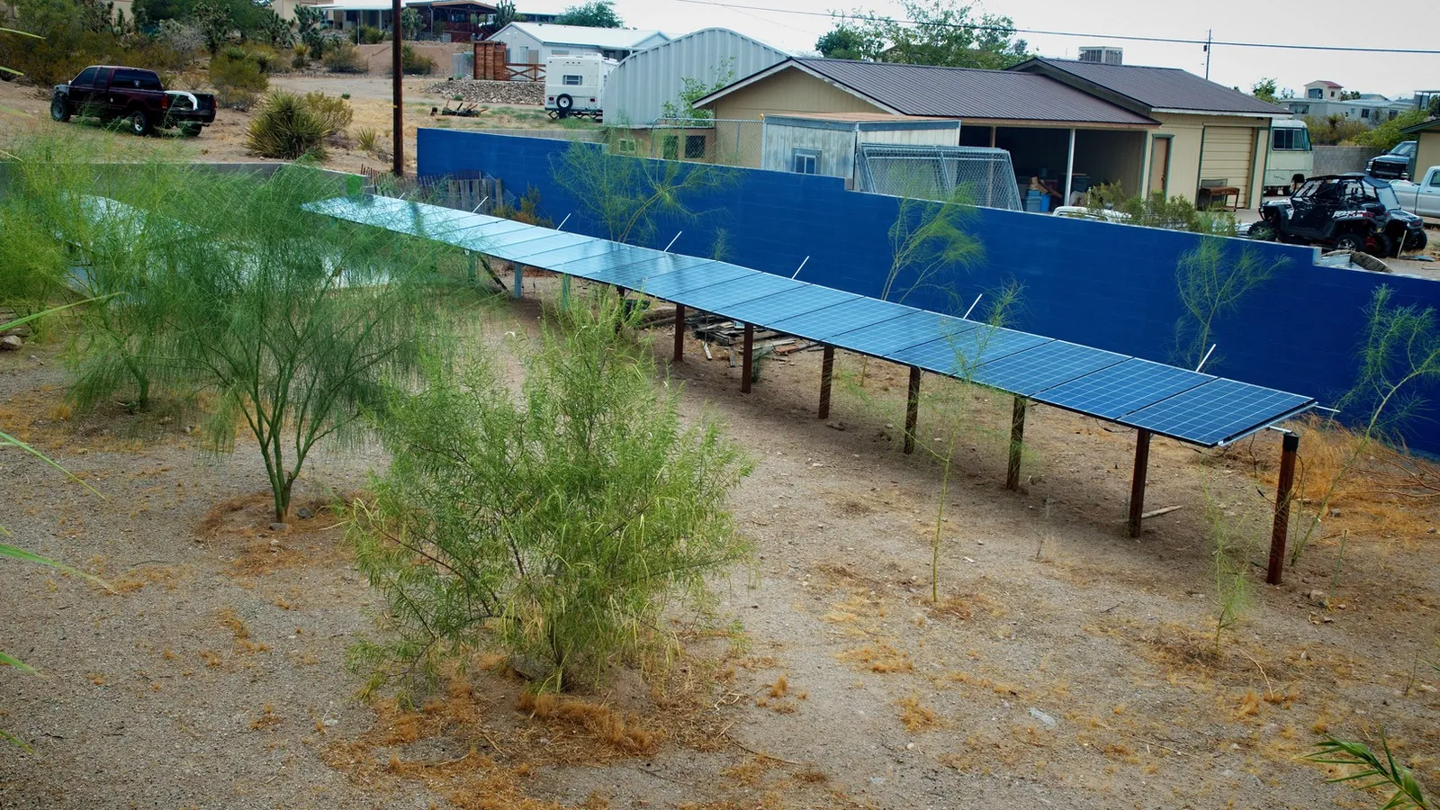 July 2024 Solar Panels between the trees and blue wall